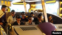 Staff members wearing virtual reality goggles sit in a motorized cart while performing an inspection of the attraction "Fly Over Guizhou," at the Oriental Science Fiction Valley theme park in Guiyang, Guizhou province, China, Nov. 16, 2017. 