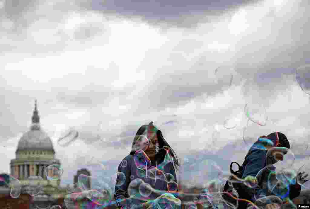 People walk through soap bubbles in front of St Paul&#39;s Cathedral in London.