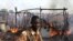 A policeman walks past the smouldering remains of a market in Rubkona near Bentiu in South Sudan, April 23, 2012. 