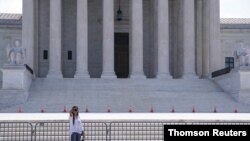 A woman takes a photo outside the Supreme Court building ahead of rulings on payments to student-athletes, in Washington, June 21, 2021. (Reuters)