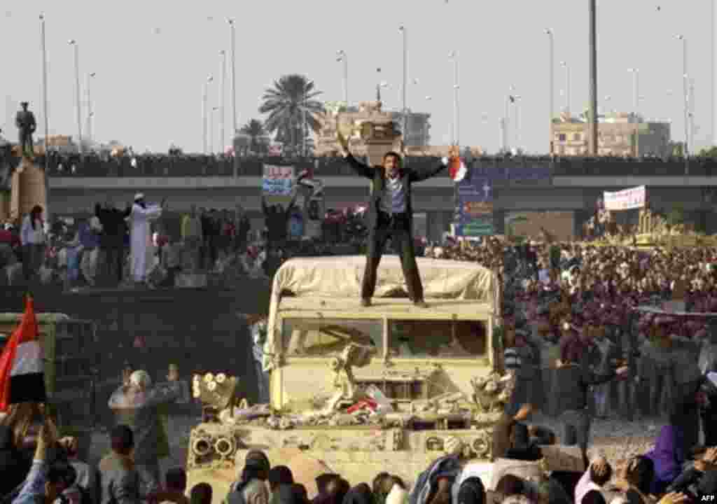 A demonstrator atop a military vehicle tries to calm the crowd, as pro-government demonstrators clash with anti-government protestors during a demonstration in Cairo, Egypt, Wednesday, Feb.2, 2011. Several thousand supporters of President Hosni Mubarak, i