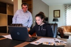 In this photo taken on May 5 2020, Aloise Hamelin,14, and her history and geography teacher Mayeul Mace, check a computer at her home in Dives-sur-Mer, Normandy.