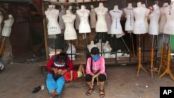 FILE - Women sit in front of mannequins at a textile market shuttered due to the coronavirus pandemic, in Jakarta, Indonesia, April 30, 2020. 