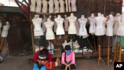 FILE - Women sit in front of mannequins at a textile market shuttered due to the coronavirus pandemic, in Jakarta, Indonesia, April 30, 2020. 