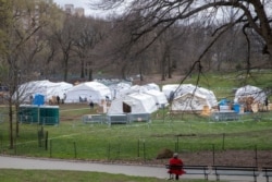 A woman watches as the Samaritan's Purse crew and medical personnel work on preparing a 68 bed emergency field hospital specially equipped with a respiratory unit in New York's Central Park, March 31, 2020.