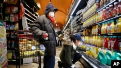 Francisco RamÃ­rez, left, and Sandra Perez, right, shop at a grocery store for goods they intend to donate to needy families, Saturday, April 18, 2020, in the Harlem neighborhood of New York. 