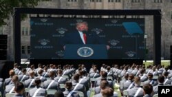 A screen displays President Donald Trump as he speaks to over 1,110 cadets in the Class of 2020 at a commencement ceremony on the parade field, at the United States Military Academy in West Point, N.Y., June 13, 2020.
