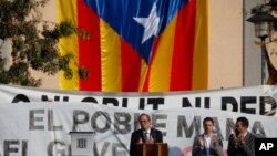 Catalan regional President Quim Torra, centre, applauds in front of a large Catalonia independence flag during a rally in Sant Julia de Ramis, Spain, Oct. 1, 2018.