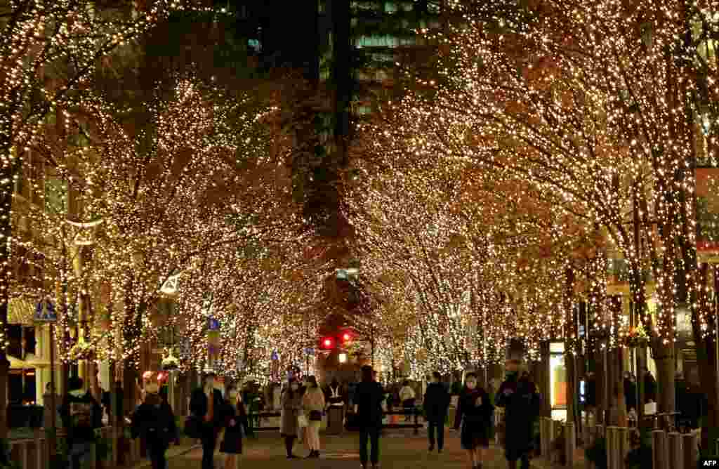 People walk under winter-themed illumination, lit by approximately 1.2 million &quot;champagne gold&quot; LED lights in the Marunouchi business district of Tokyo, Japan.