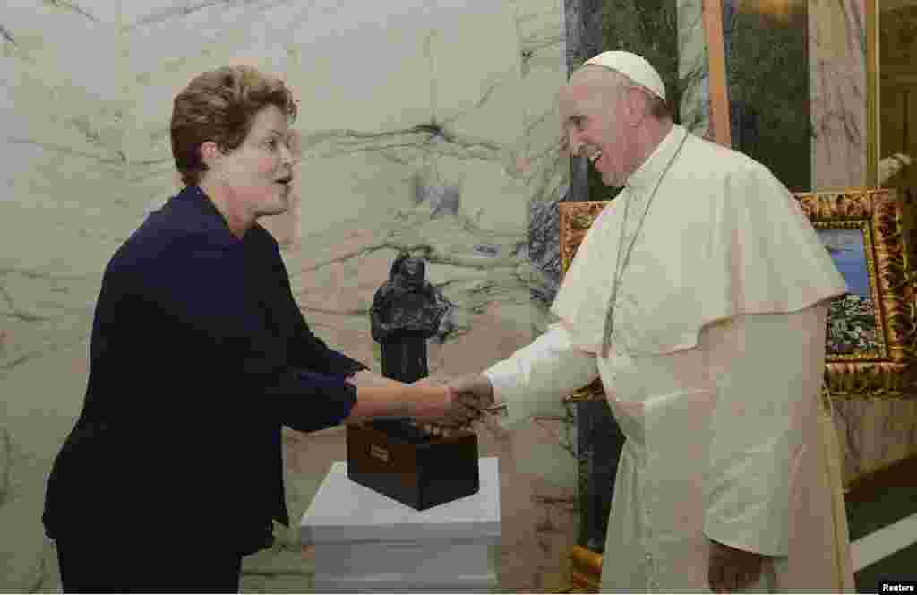 Paus Fransiskus bersalaman dengan Presiden Brazil Dilma Rousseff setelah menerima lukisan Rio de Janeiro dalam upacara penyambutan di Rio de Janeiro (22/7).