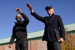 El candidato presidencial demócrata, exvicepresidente Joe Biden (der.) y el expresidente Barack Obama saludan a partidarios durante un evento de campaña en la secundaria Northwestern en Flint, Michigan, el sábado 31 de octubre de 2020.