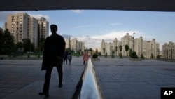 A man walks past a metal fence reflecting the sky on his way to a polling station in Bosnia to cast his ballot in the country's general elections in Sarajevo, Bosnia, on Sunday, Oct. 7, 2018.