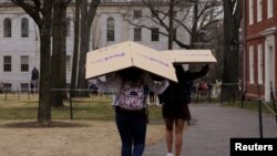 Para siswa membawa kotak-kotak ke asrama mereka di Universitas Harvard. Kampus meminta mereka tidak kembali ke kampus setelah liburan musim semi dan belajar dilakukan secara online, Cambridge, Massachusetts, AS, 10 Maret 2020. (Foto: Reuters/Brian Snyder)