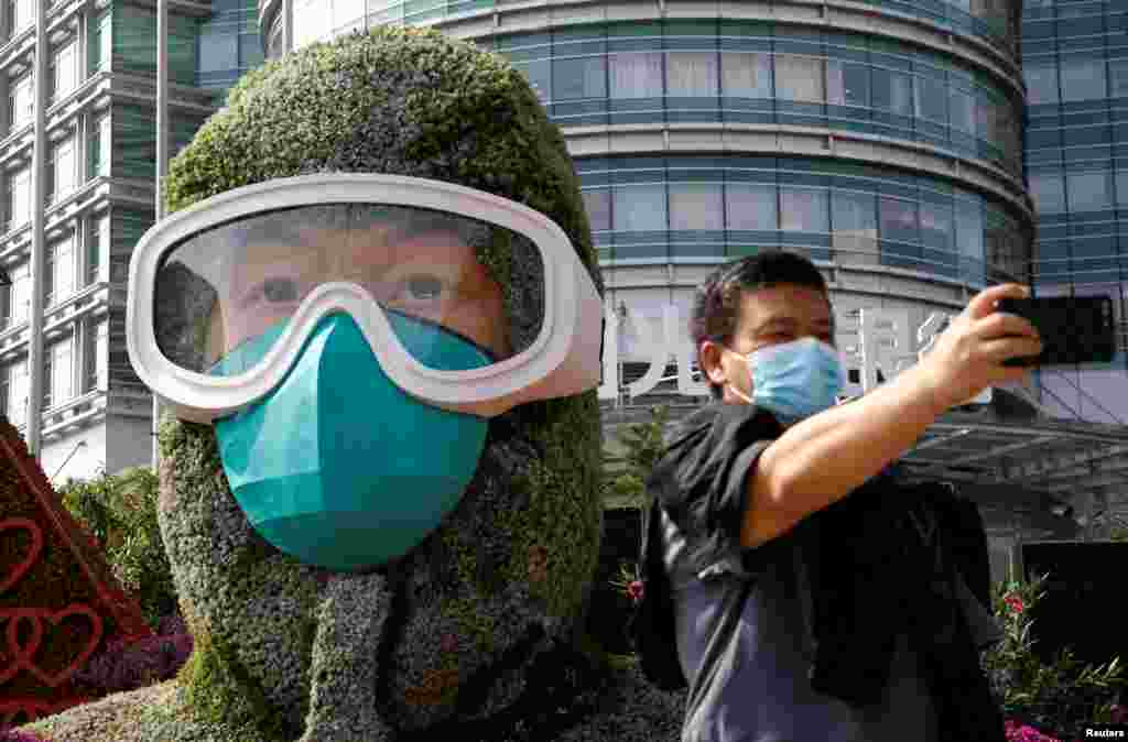 A man wearing a face mask takes selfies in front of a floral installation featuring a medical worker in the fight against the coronavirus disease, set up ahead of Chinese National Day on October 1, on Changan Avenue in Beijing, China.