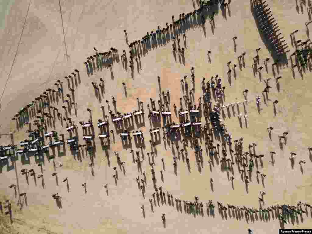 An aerial picture shows mourners carrying coffins during a mass funeral for Yazidi victims of the Islamic State (IS) group whose remains were found in a mass grave, in the northern Iraqi village of Kojo in Sinjar district, Dec. 9, 2021. 