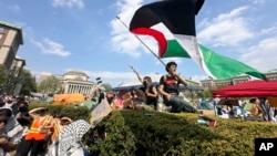 FILE - A demonstrator waves a flag on the Columbia University campus at a pro-Palestinian protest encampment, in New York, April 29, 2024.