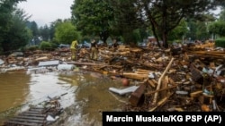 This handout photo provided by the Polish fire department shows firefighters removing debris dumped in the streets by a flood wave passing through southwestern Poland, in Glucholazy, Poland, Sept. 17, 2024. (Marcin Muskala/KG PSP via AP)