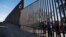 Boys look through an older section of the border structure from Mexicali, Mexico, alongside a newly constructed, taller section, left, in Calexico, Calif., March 5, 2018. President Trump tweeted about new work on the border wall, but this work began in February and wasn't funded by the budget he just signed.