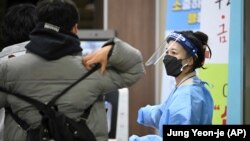 A school teacher wearing protective gear guides a South Korean student before the start of the College Scholastic Ability Test at a high school in Seoul, Nov. 18, 2021. (Jung Yeon-je/Pool Photo via AP)