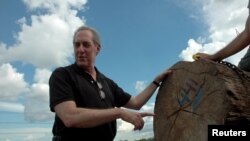 FILE - U.S. Trade Representative Michael Froman looks at wood being inspected at a checkpoint designed to curb illegal logging in the region of Pucallpa, Peru, May 16, 2016.