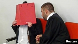 FILE - Defendant Jennifer W. covers her face as she waits for the start of the trial beside her lawyer, Ali Aydin, in Munich, Germany, April 9, 2019.