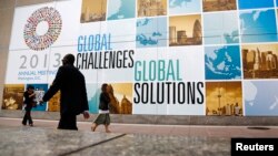 People walk outside the International Monetary Fund headquarters at the start of the annual IMF-World Bank fall meetings in Washington, Oct. 8, 2013. 