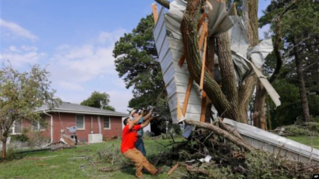 Residentes en Bennet, Nebraska, tratan de desprender la sección lateral de una casa incrustada en un árbol.