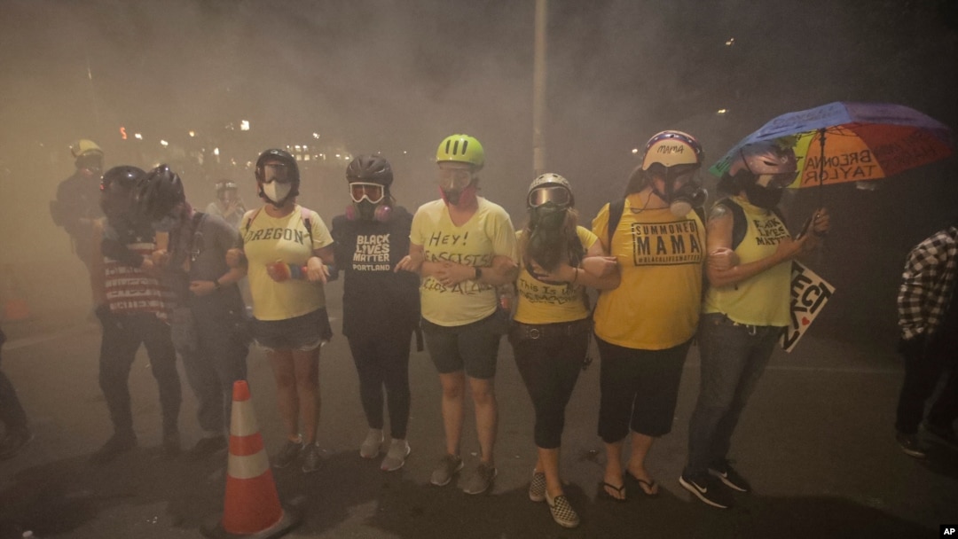 Members of the 'Wall of Moms' protest group lock arms as they are tear-gassed by federal officers during a Black Lives Matter protest at the Mark O. Hatfield United States Courthouse, July 27, 2020, in Portland, Ore.