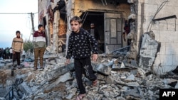 İsrail'in Refah saldırılarında ağır hasar göre bir binanın enkazında yürüyen insanlar - 11 Şubat 2024.