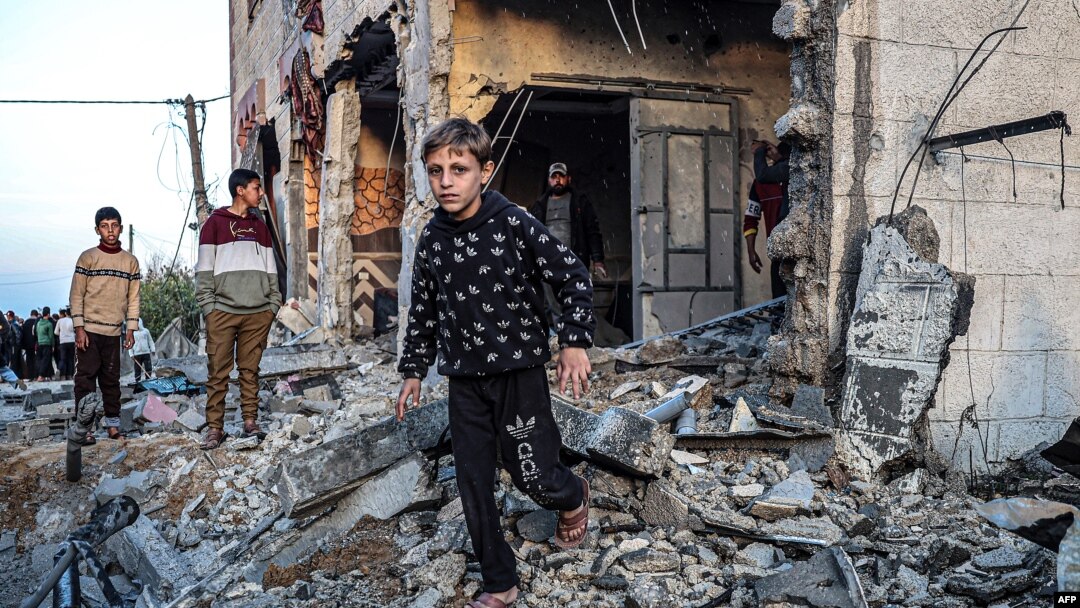 Warga berjalan melewati puing-puing bangunan yang rusak berat akibat pengeboman Israel, di Rafah di selatan Jalur Gaza pada 11 Februari 2024. (Foto: AFP)