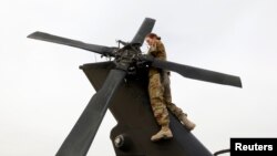 FILE - A U.S. Army soldier performs a system check on a helicopter at the beginning of her shift in Logar province, eastern Afghanistan, Nov. 21, 2011. 