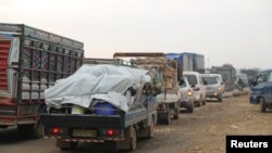 FILE - Trucks carry belongings of people fleeing from Maarat al-Numan, in Idlib province, Syria, Dec. 24, 2019.