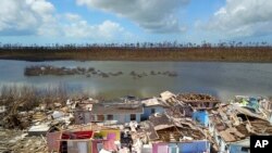 FILE - A Haitian migrant walks among the ruins of a neighborhood destroyed by Hurricane Dorian in Sandbank, Abaco, Bahamas, Sept. 28, 2019.