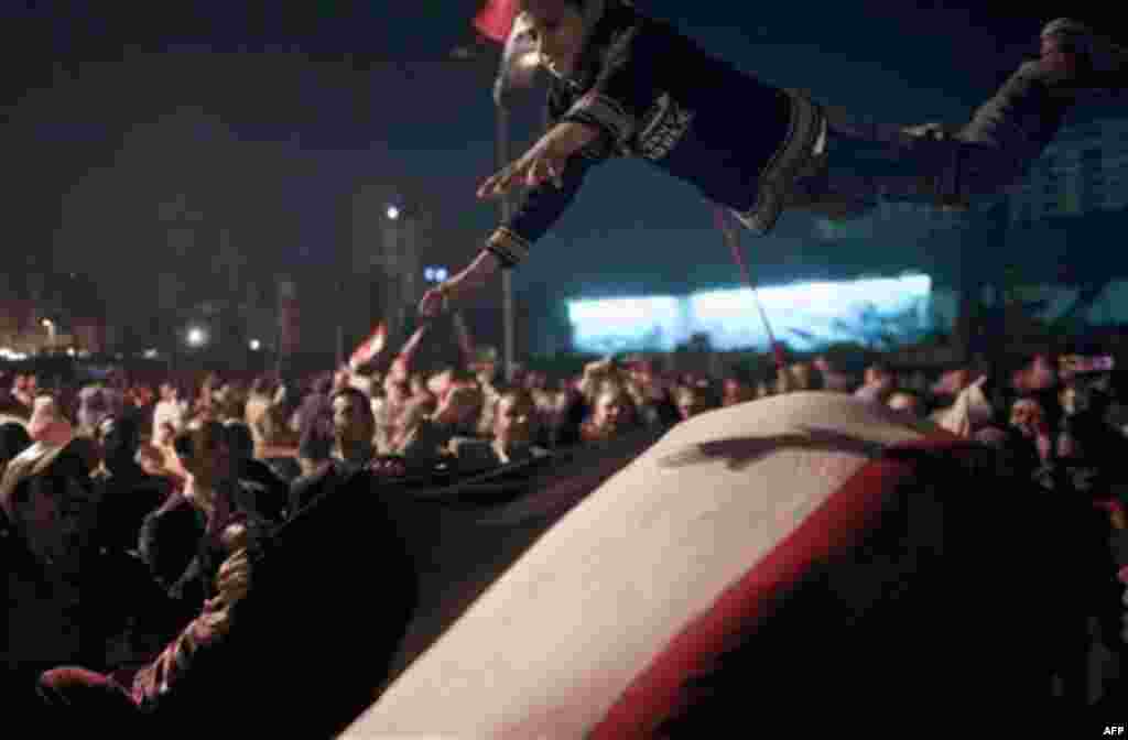 Egyptians toss a boy in the air as they celebrate the news of the resignation of President Hosni Mubarak, who handed control of the country to the military, at night in Tahrir Square in downtown Cairo, Egypt Friday, Feb. 11, 2011. Fireworks burst over Tah