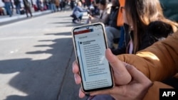 An asylum seeker shows an updated message on the CBP One app mentioning that all appointments have been cancelled as they wait for their CBP One appointment with U.S. authorities before crossing through El Chaparral port in Tijuana, Baja California state, Mexico, Jan. 20, 2025. 