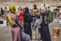 In this image provided by the U.S. Marine Corps, Marines with the 24th Marine Expeditionary Unit process evacuees as they go through the evacuation control center at Hamid Karzai International Airport in Kabul, Afghanistan, Aug. 28, 2021.