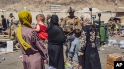 In this image provided by the U.S. Marine Corps, Marines with the 24th Marine Expeditionary Unit process evacuees as they go through the evacuation control center at Hamid Karzai International Airport in Kabul, Afghanistan, Aug. 28, 2021.