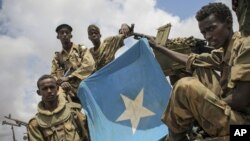 Soldiers of the Somali National Army (SNA) are seen displaying the Somali national flag in Saa'moja, around 7km north-west of the port city of Kismayo, in southern Somalia, Monday, Oct. 1, 2012. (AP Photo/AU-UN IST, Stuart Price)