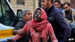 Syrian men help a wounded woman covered in dust following a strike in the town of Khan Shaykhun in the southern countryside of the rebel-held Idlib province, Feb. 15, 2019.