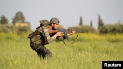 FILE - A rebel fighter is seen aiming his weapon in the countryside near Aleppo, Syria.