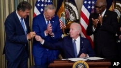 President Joe Biden hands the pen he used to sign the climate change and health care bill to Sen. Joe Manchin, D-W.Va., in the State Dining Room of the White House in Washington, Tuesday, Aug. 16, 2022. (AP Photo/Susan Walsh)