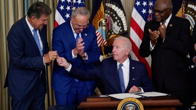 President Joe Biden hands the pen he used to sign the climate change and health care bill to Sen. Joe Manchin, D-W.Va., in the State Dining Room of the White House in Washington, Tuesday, Aug. 16, 2022. (AP Photo/Susan Walsh)