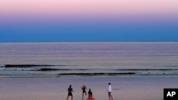 FILE - A group of people play on the beach in Ocean Park, Maine, Aug. 7, 2020. A new study offers evidence on how water originated on Earth.