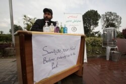 A government worker on a stall offers hand sanitizer as a preventive measure against coronavirus, to the people visiting a park in Lahore, Pakistan, March 14, 2020.