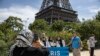 FILE - Tourists pose in front of the Eiffel Tower in the background in Paris on August 4, 2024, during the Paris 2024 Olympics games. 