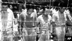 Japanese prisoners of war at Guam, Mariana Islands, bow their heads as they hear Japanese Emperor Hirohito making the announcement of Japan's unconditional surrender on August 15, 1945. (AP Photo)