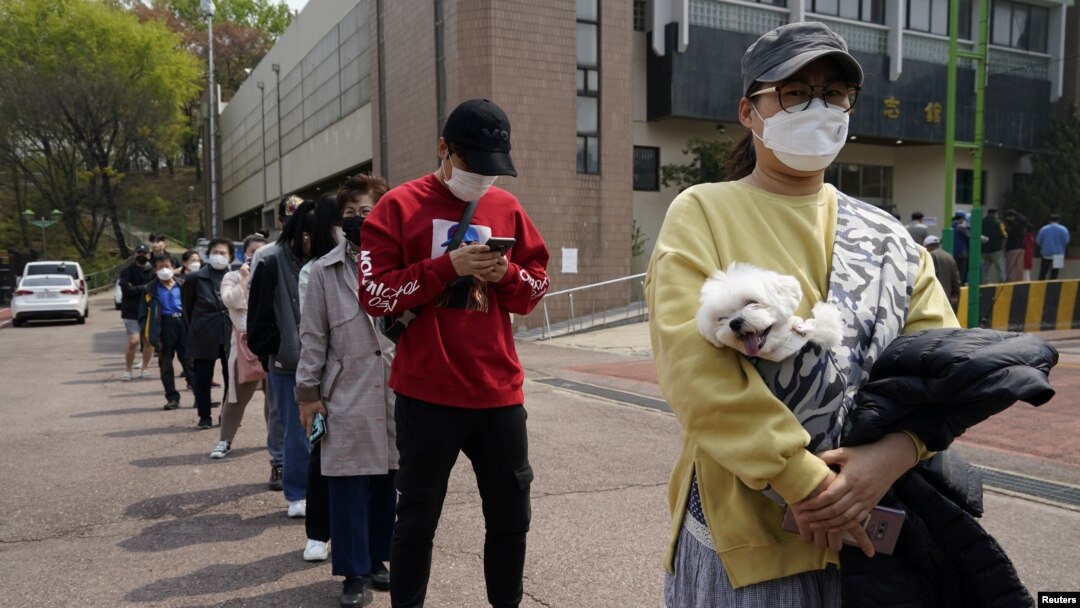 Warga Korea Selatan dengan tetap menjaga jarak dan mengenakan masker, antri untuk memberikan suara di sebuah TPS di Seoul, Rabu (15/4). 