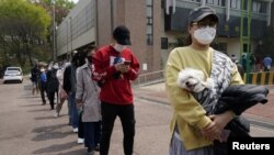 Warga Korea Selatan dengan tetap menjaga jarak dan mengenakan masker, antri untuk memberikan suara di sebuah TPS di Seoul, Rabu (15/4). 