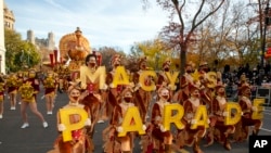 FILE - Dancers wearing face masks and dressed as Thanksgiving turkeys hold letters that spell Macy's Parade in New York City at the front of the Macy's Thanksgiving Parade on Thursday, Nov. 25, 2021. 