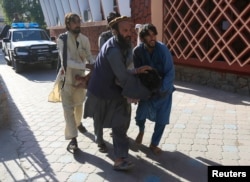 Afghan men carry a wounded person to the hospital after a suicide attack in Jalalabad, Afghanistan, June 13, 2019.